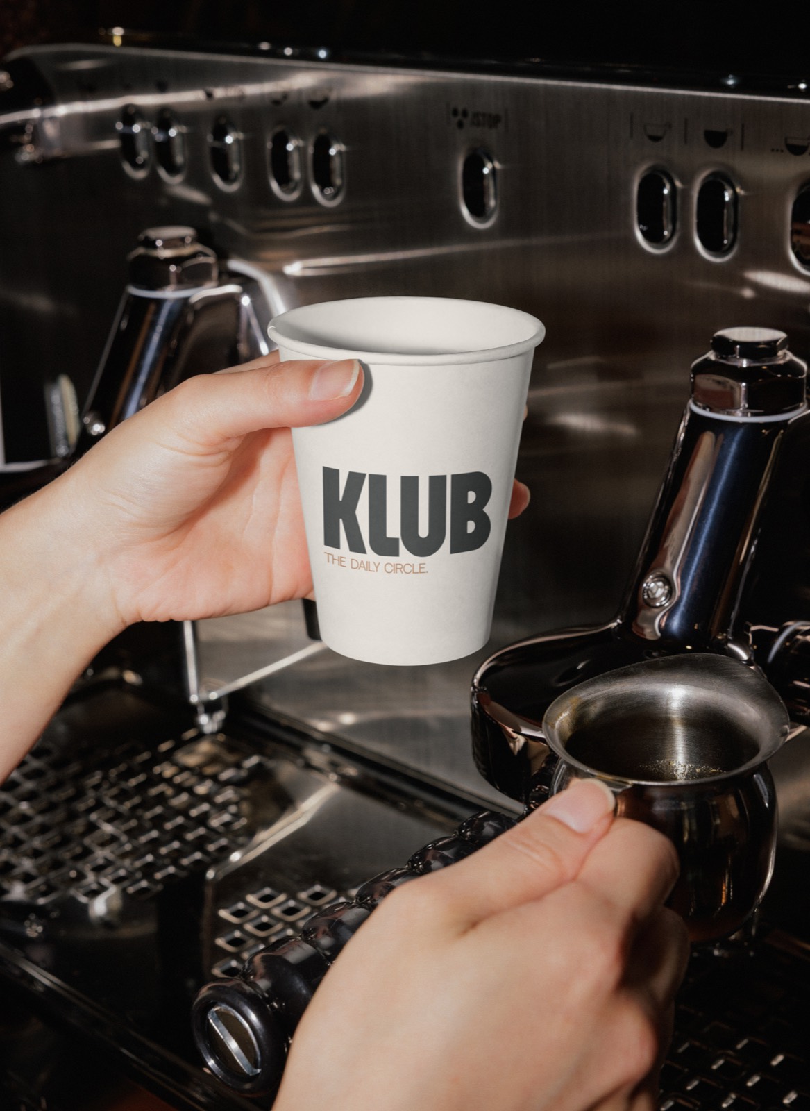 Gobelet KLUB tenu devant une machine à espresso