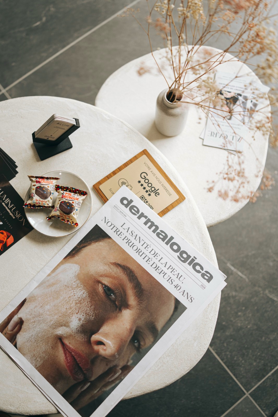 Table d'accueil du studio : magazine Dermalogica, bougie et carte d'avis