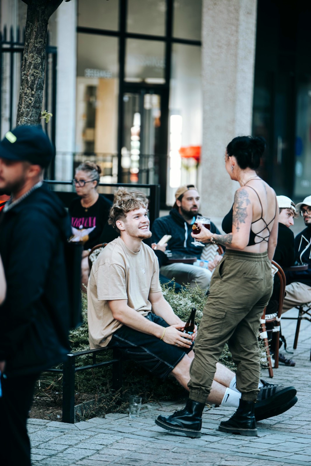 Terrasse en fin de journée : un client attablé, une serveuse qui passe entre les tables