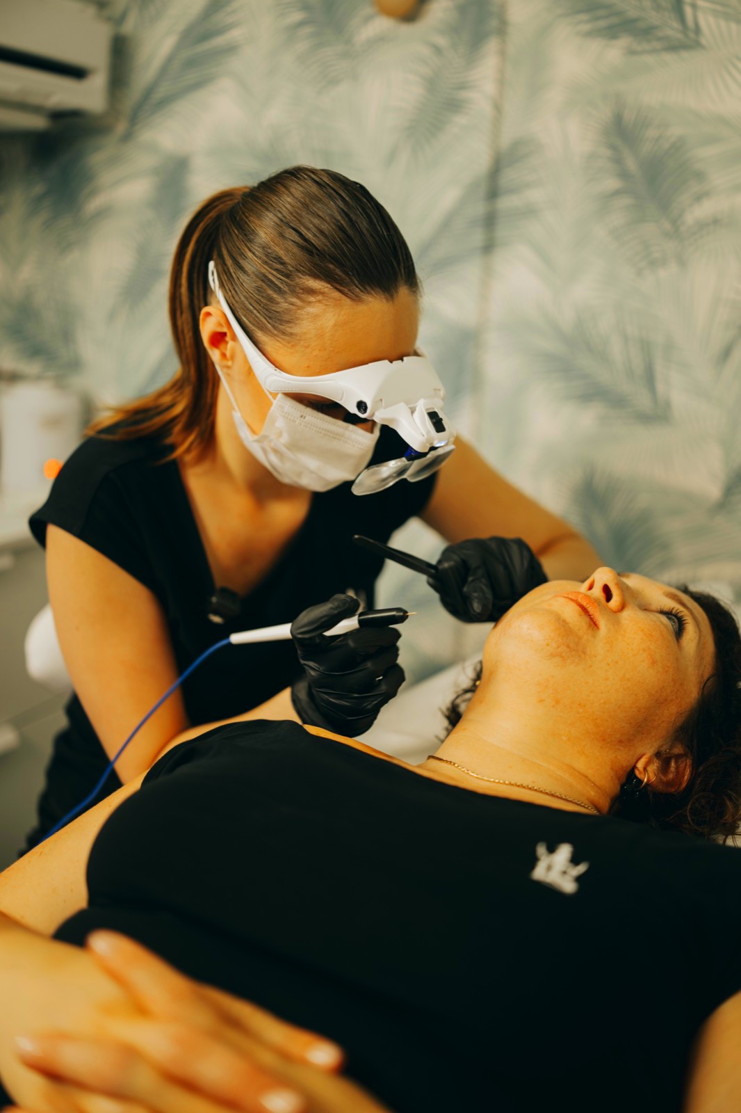 Esthéticienne masquée travaillant au visage d'une cliente allongée