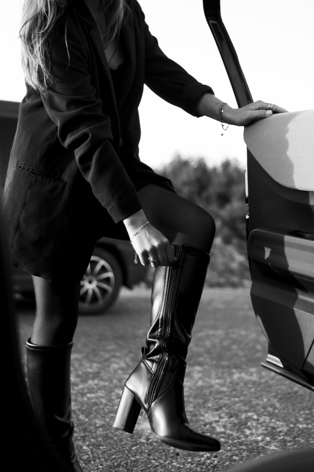 Détail en noir et blanc de bottes vernies devant la MINI