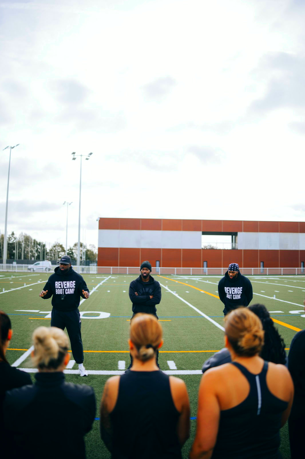 Briefing d'avant-séance : trois coachs face au groupe, au milieu du terrain