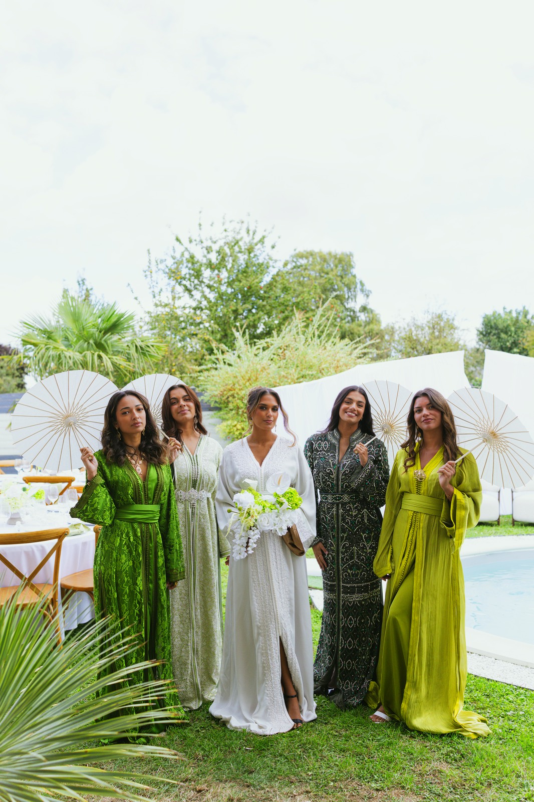Invitées en caftans, ombrelles à la main, au bord du bassin